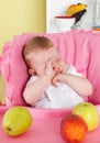 Sleepy baby girl in the high chair