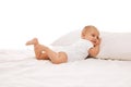 Sleepy baby. Smiling, happy little girl, toddler lying on bed on comfortable pillow against white background Royalty Free Stock Photo