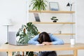 Sleepy bored woman office worker lying on table with laptop, feeling lack of energy sitting at workplace Royalty Free Stock Photo