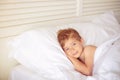 A boy quietly laying in bed in his room, putting hand under his head.