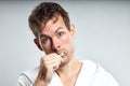 Sleepy caucasian guy brushing tooth wearing bathrobe, isolated on gray Royalty Free Stock Photo