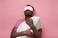 Sleepy dark haired man in mask holding white pillow