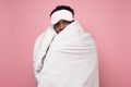 Sleepy dark haired man in medical mask holding white blanket