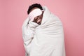 Sleepy dark haired man in medical mask holding white blanket