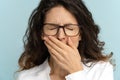 Sleepy employee office woman wear glasses bored, yawn with closed eyes, covers mouth with hand