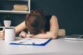 Sleepy exhausted woman in office with cup of coffee in her hand.