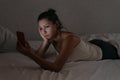 Sleepy female looking at her smartphone in bed at night