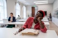 Sleepy lazy African American man falls asleep sits in library with head resting on desk with books Royalty Free Stock Photo