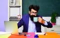 Sleepy male student working with laptop and drinking coffee in classroom. Teacher or university professor at workplace