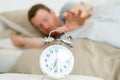 sleepy man reaching to snooze alarm clock Royalty Free Stock Photo