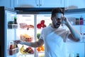 Sleepy man taking juice out of refrigerator at night Royalty Free Stock Photo