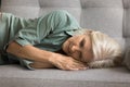 Sleepy napping blonde senior woman lying on side on couch Royalty Free Stock Photo