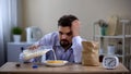 Sleepy overworked bachelor eating corn flakes with milk in morning, fatigue