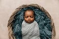 Sleepy swaddled African-American newborn baby boy