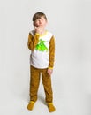 Sleepy and tired blond little cute boy wearing pajamas yawning. Kid boy in pyjamas with dinosaur animal print stands and Royalty Free Stock Photo