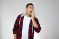 Sleepy tired funny young Asian man yawning, sleeping while standing, half body portrait