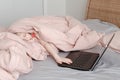 Sleepy tired girl lying in bed under blanket, learning in virtual online school class. Kid working on laptop Internet at home. Royalty Free Stock Photo