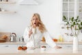 Sleepy tired lazy young pretty caucasian blonde lady in bathrobe wakes up early, drink coffee and yawns Royalty Free Stock Photo