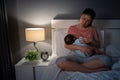 sleepy and tired mother breastfeeding newborm baby on bed at night Royalty Free Stock Photo