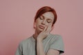 Sleepy tired red-haired woman dozing on hand, falling asleep, isolated over pink background