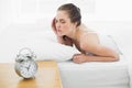 Sleepy woman in bed with alarm clock in foreground Royalty Free Stock Photo