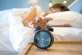 Sleepy woman in bed switching off alarm clock, Selective focus