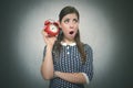 Sleepy woman with red alarm clock on gray background.