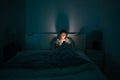 Sleepy woman lying in bed using smartphone late at night, can not sleep. Insomnia, addiction concept Royalty Free Stock Photo