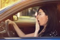 Sleepy yawning woman driving her car after long hour trip.