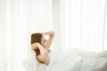 Sleepy young asian woman stretching and waking up in her bedroom at home in the morning Royalty Free Stock Photo