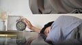 Sleepy man lying on the bed and stopping alarm clock. Royalty Free Stock Photo