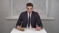 A sleepy young man in a suit eats cereal and drinks coffee and is invigorated. Young businessman at home in the kitchen.