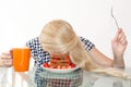 Sleepy young woman had breakfast and put her head in a plate, fell asleep in a plate. The concept of early morning, heavy morning.