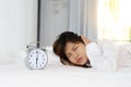 Sleepy young woman looking at alarm clock with hands covering he Royalty Free Stock Photo