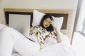 A sleepy young woman yawning while working from the bed Royalty Free Stock Photo