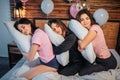 Sleepy young women sitting on bed in room. Their head lying on pillows they have in hands. They sleep. Models smile Royalty Free Stock Photo