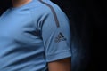front of the sports blue t-shirt with the logo of the german company adidas on an isolated background