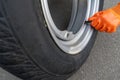 A sleeve of orange gloves twists off the nipple cover on a car wheel Royalty Free Stock Photo