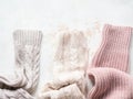 Sleeves of three of warm different knitted woolen sweaters pastel shades beige textured background. Top view