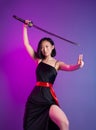 slender Asian woman in a black dress with a katana in her hand image of a samurai on a neon background