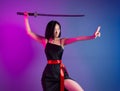 slender Asian woman in a black dress with a katana in her hand image of a samurai on a neon background