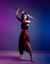 slender Asian woman in a black dress with a katana in her hand image of a samurai on a neon background