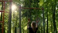 slender athletic woman takes on gymnastic rings and pulls herself up. blonde woman in park is doing workout and go in