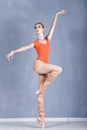 Slender ballerina rehearsing in a dance movement. On one foot on