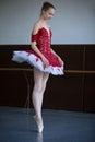 Slender ballerina standing on pointe in the ballroom looking down