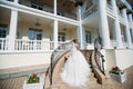 A slender bride in a wedding dress with a long train goes up the steps to the palace. The girl is holding a beautiful Royalty Free Stock Photo