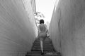 A slender brunette climbs the stairs in a narrow dangerous deserted dark alley Royalty Free Stock Photo