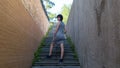 A slender brunette climbs the stairs in a narrow dangerous deserted dark alley Royalty Free Stock Photo