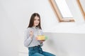 Slender brunette girl with long hair on a white background eats with a fork from a container for lunches. Color box for