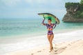 A slender brunette girl is walking along the beach, carrying a surfboard on her head Royalty Free Stock Photo